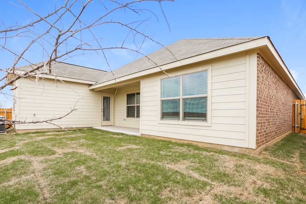 the front of a house with a yard and a brick wall