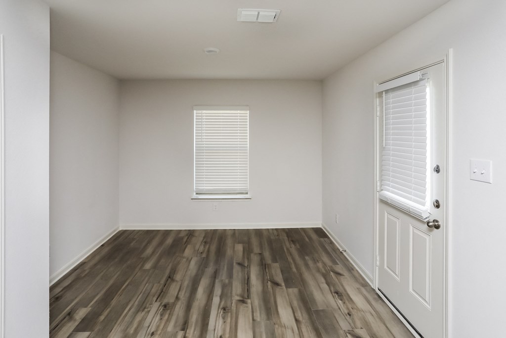 an empty room with wooden floors and white walls and a window