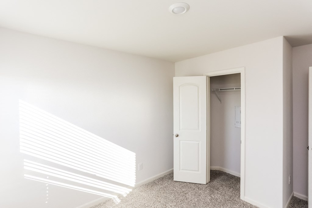 an empty room with a white door and a closet