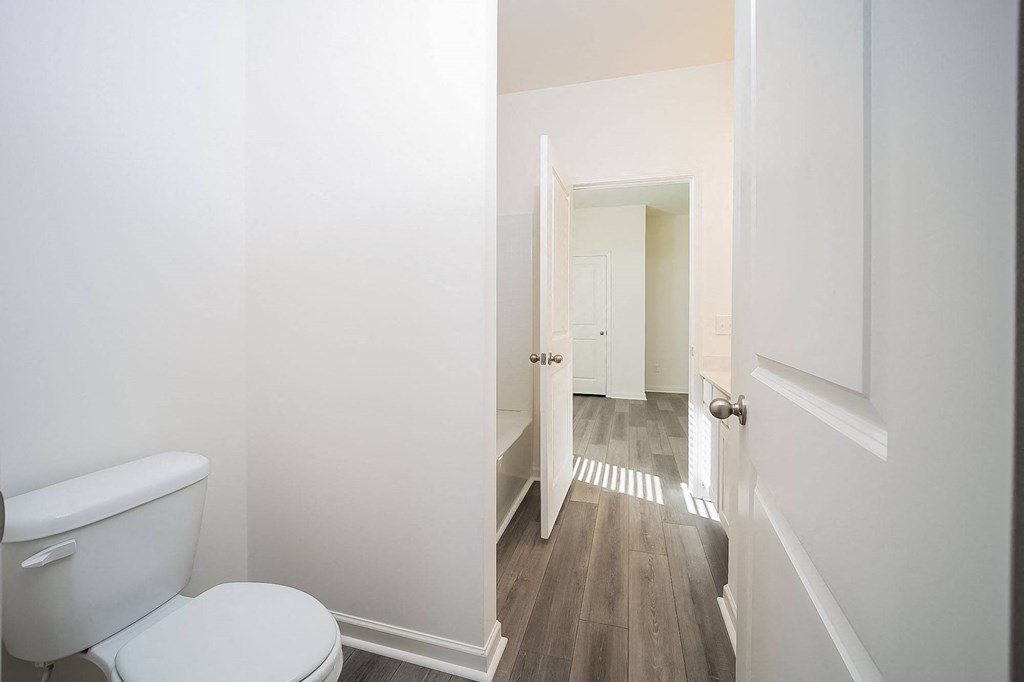 a white bathroom with a toilet and a hallway