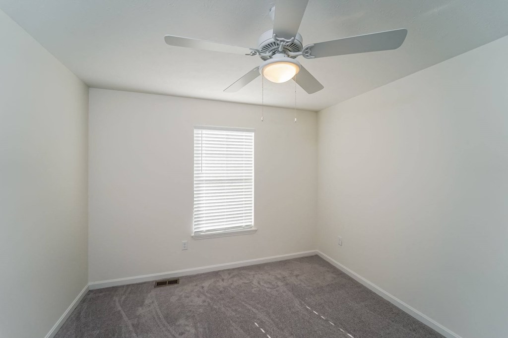 a bedroom with a ceiling fan and a window