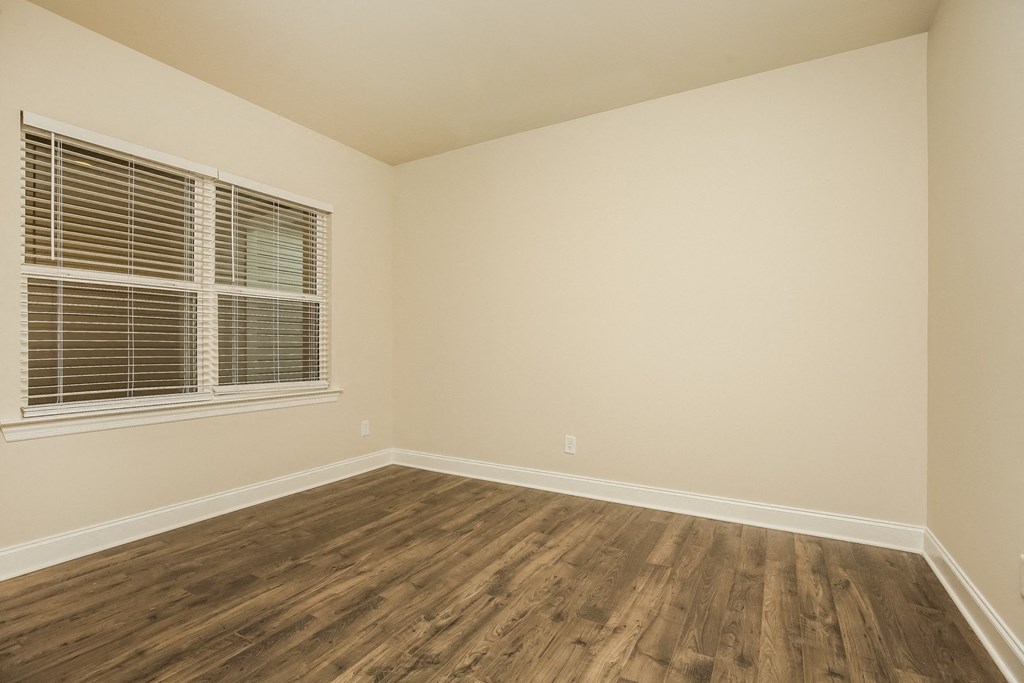 an empty bedroom with wood floors and a window