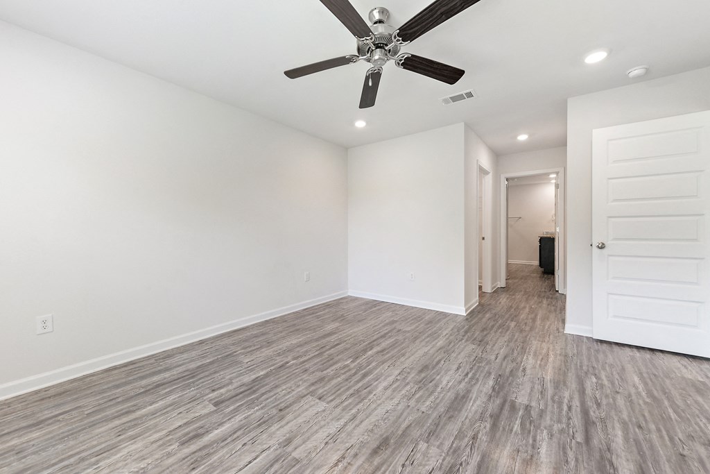an empty living room with white walls and a ceiling fan