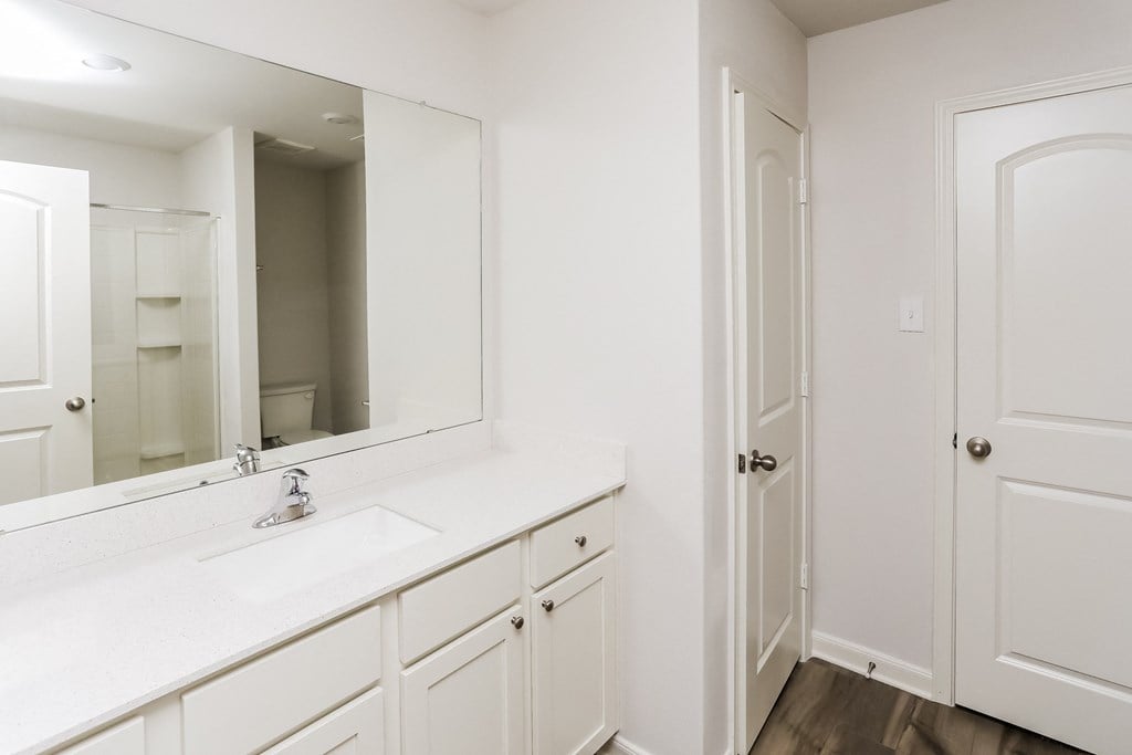 a bathroom with white cabinets and a sink and a mirror
