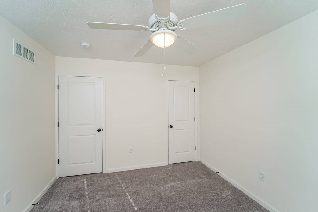 a bedroom with two doors and a ceiling fan