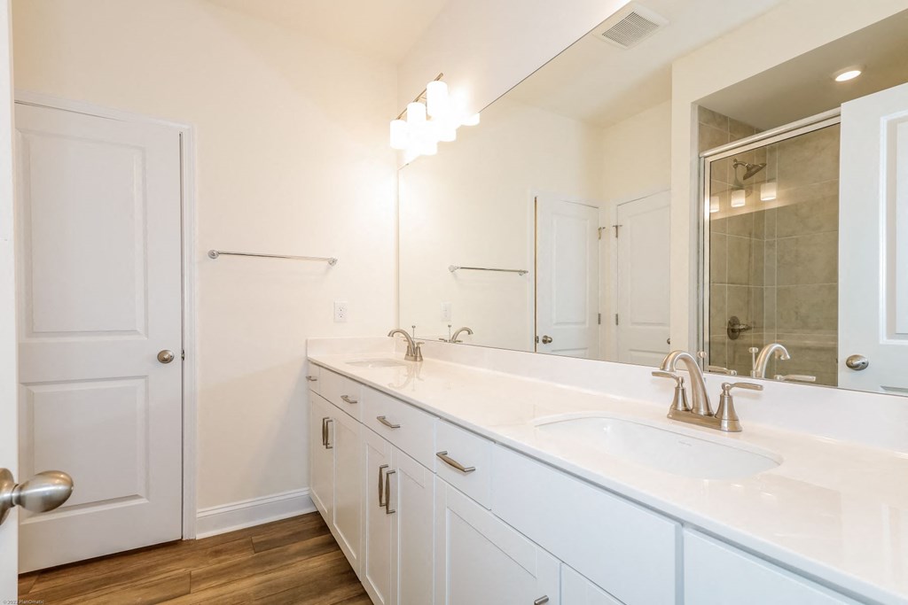 a bathroom with white cabinets and a large mirror