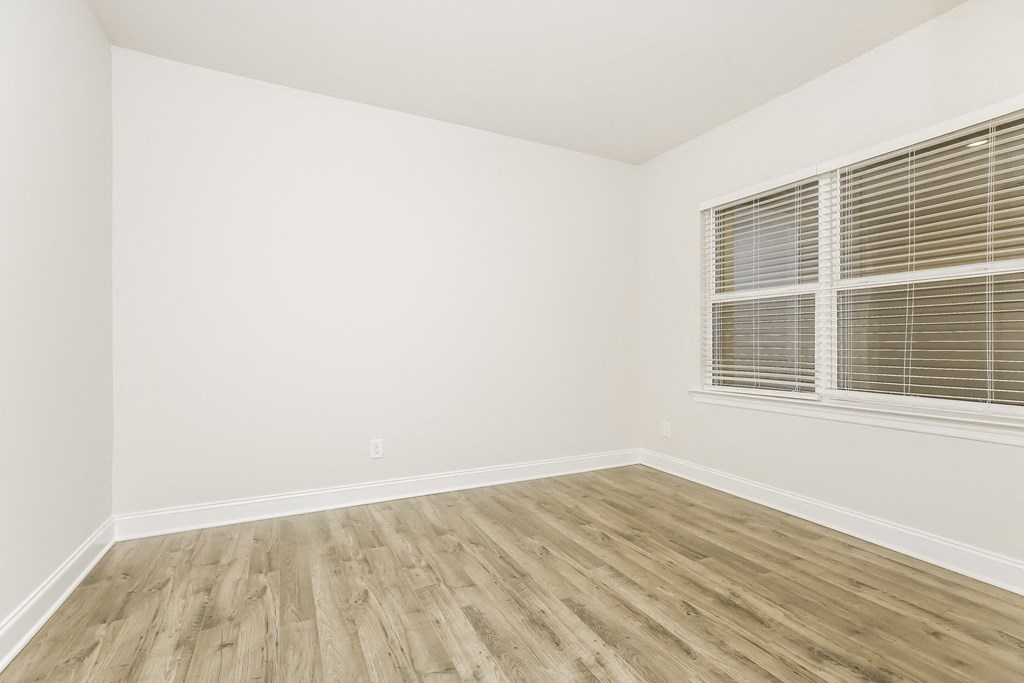 an empty room with wood floors and a window