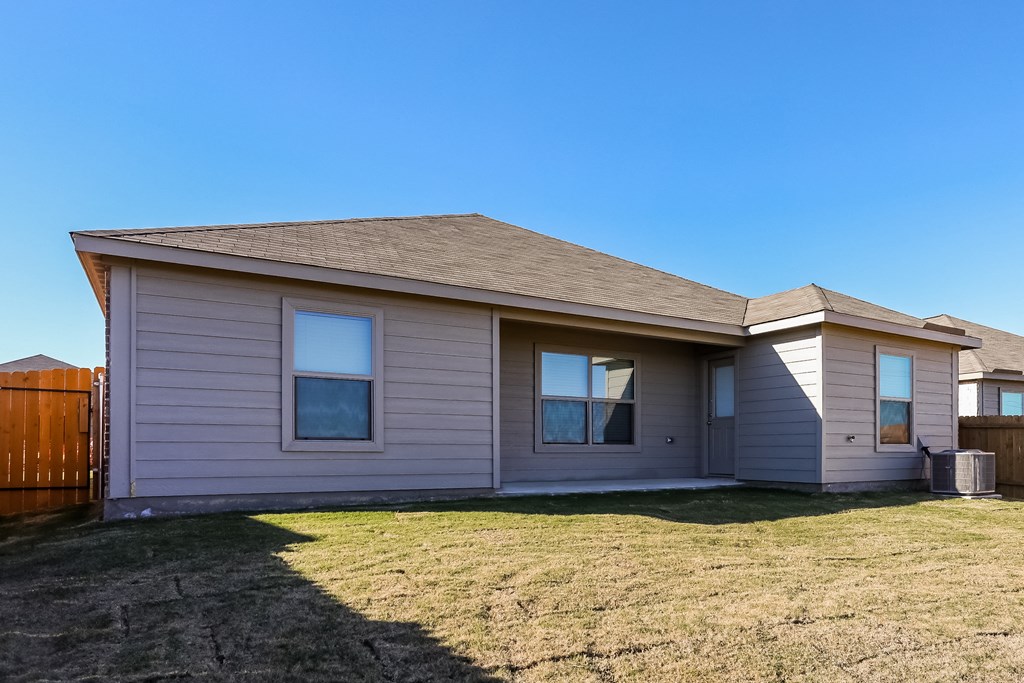 a tan house with a yard and a wooden fence