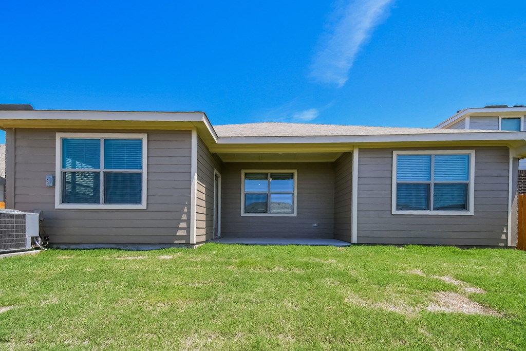 the front of a house with a lawn and a blue sky