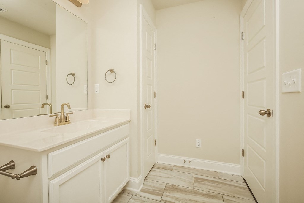 a bathroom with white cabinets and a sink and a mirror