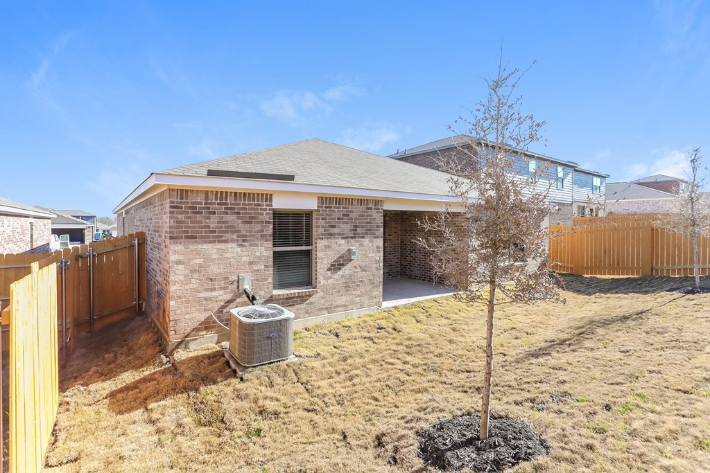 a small brick house with a yard and a fence