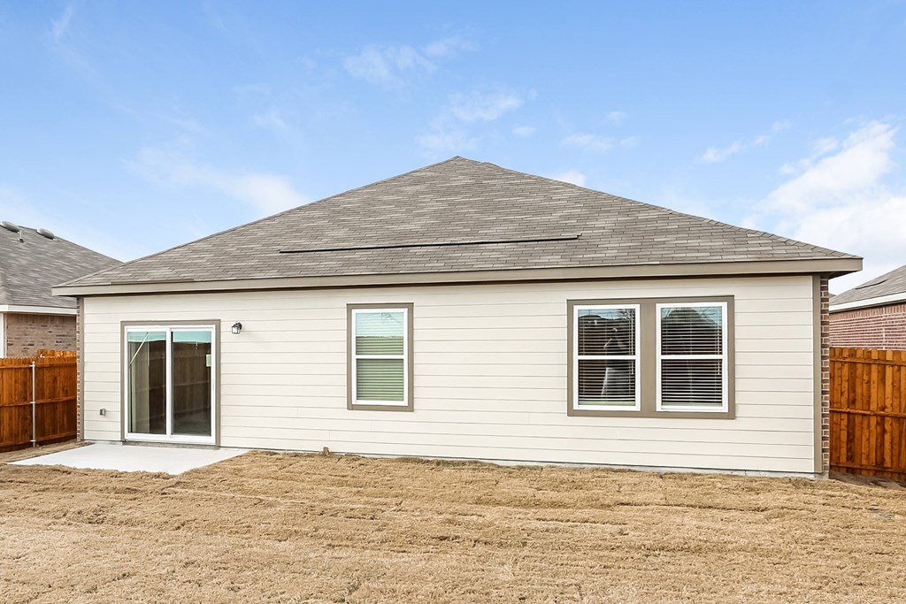 the front of a white house with a wood fence