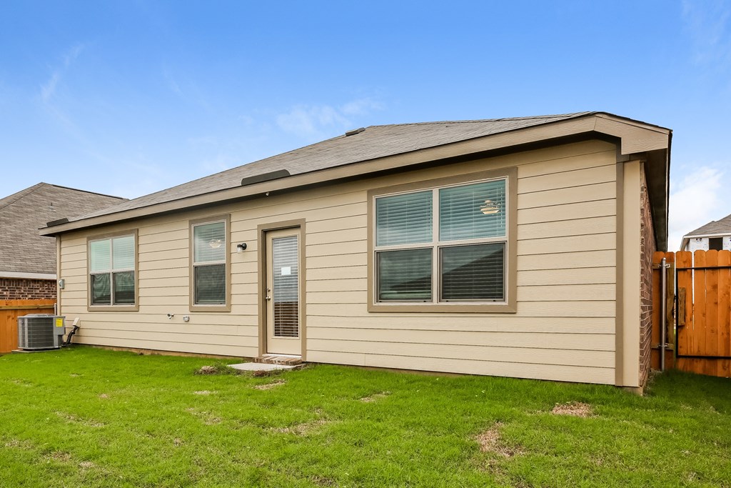 a tan house with a yard and a wooden fence