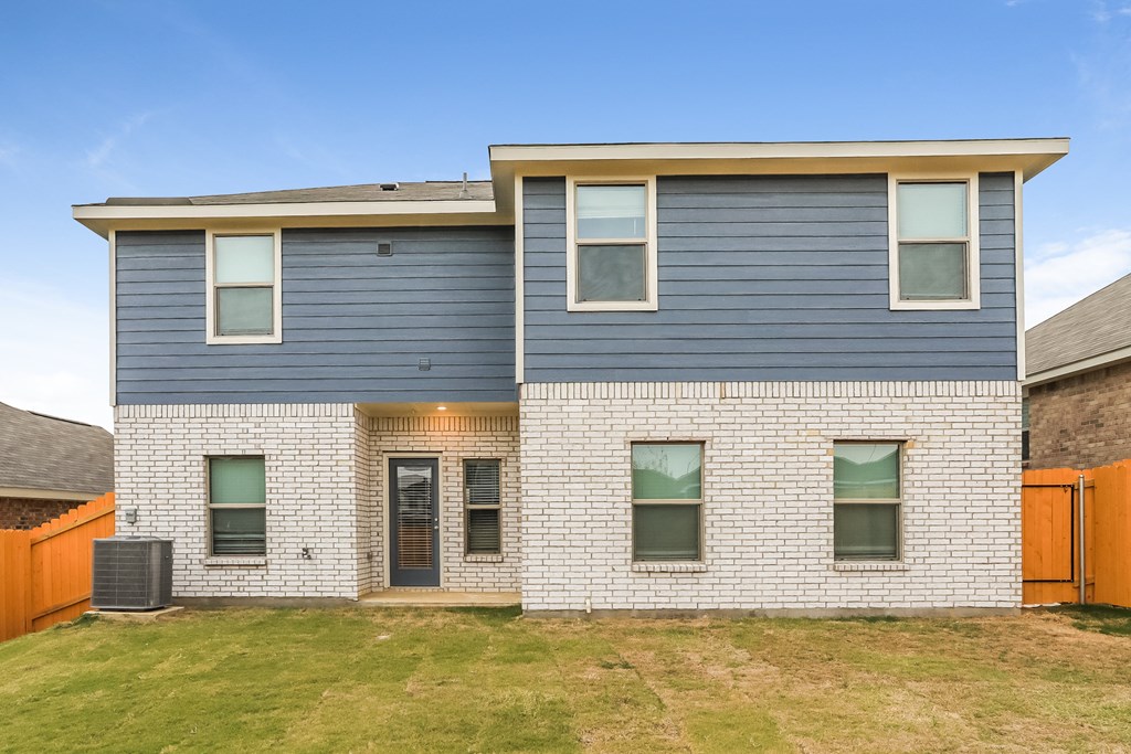 a blue and white brick house with blue siding and a yard