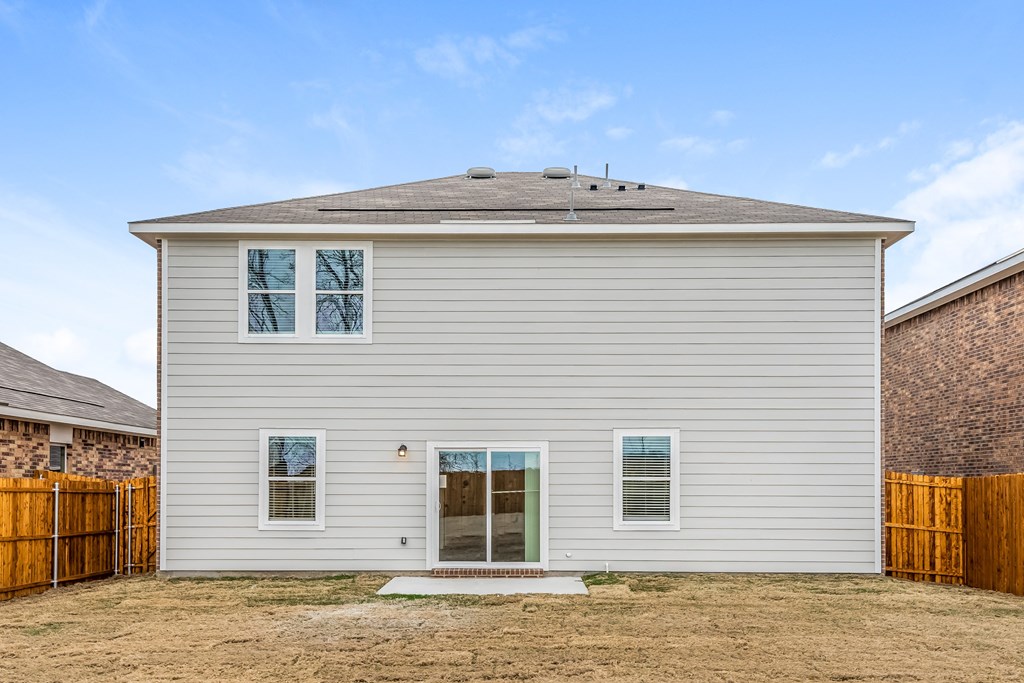 the back of a white house with a yard and a wooden fence