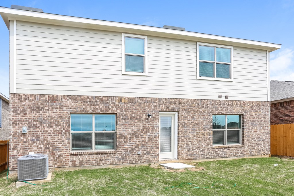 a brick house with two windows and a wood fence