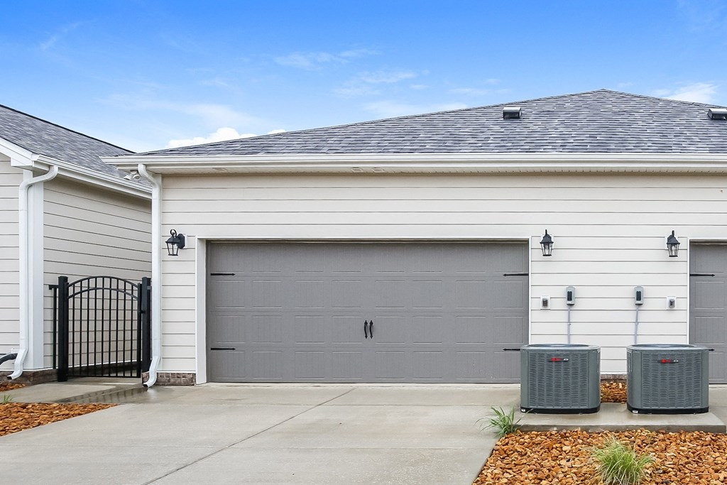 a white house with a garage door and two trash cans