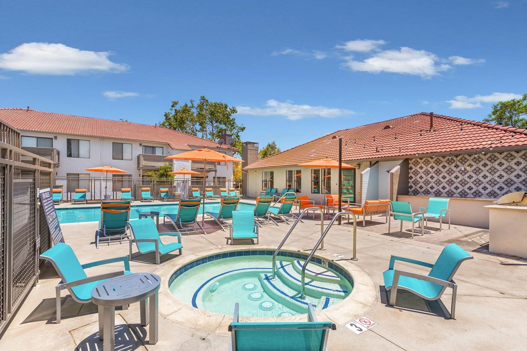 a resort style pool with blue chairs and a hot tub