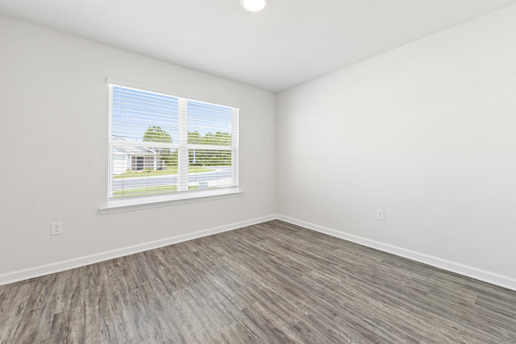 an empty room with vinyl flooring and a window