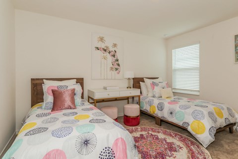 Bright primary bedroom with twin beds, desk, and Florida-themed artwork.
