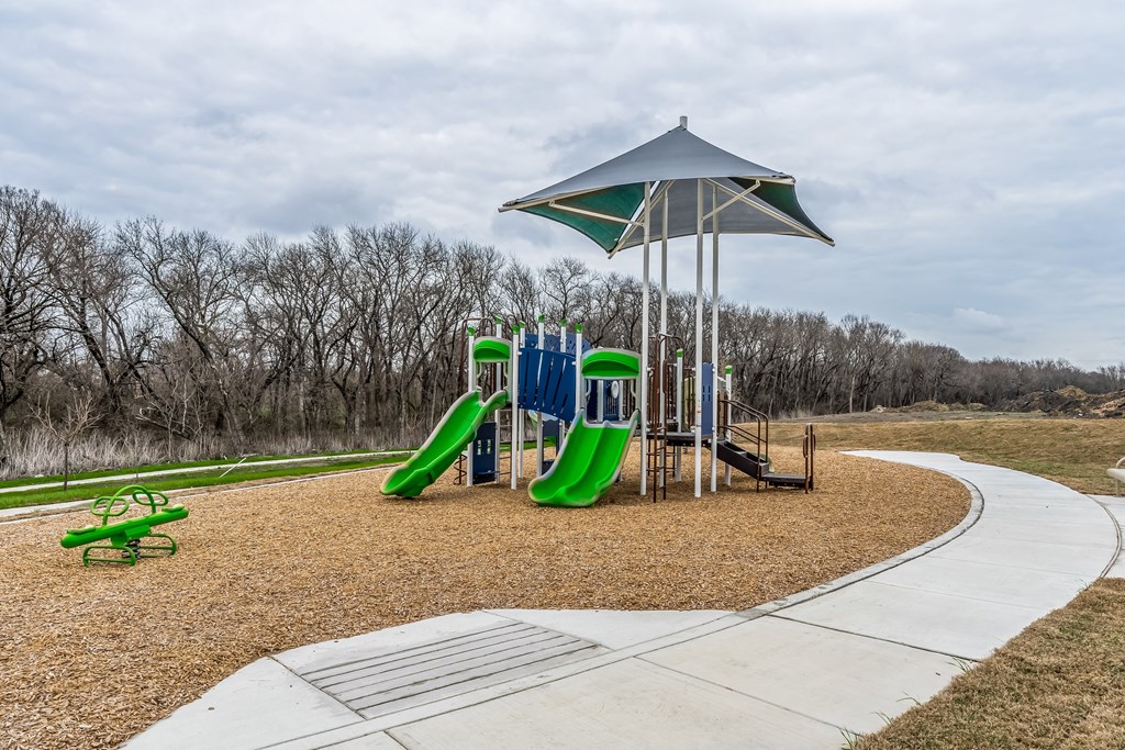 a playground with slides and a umbrella in a park