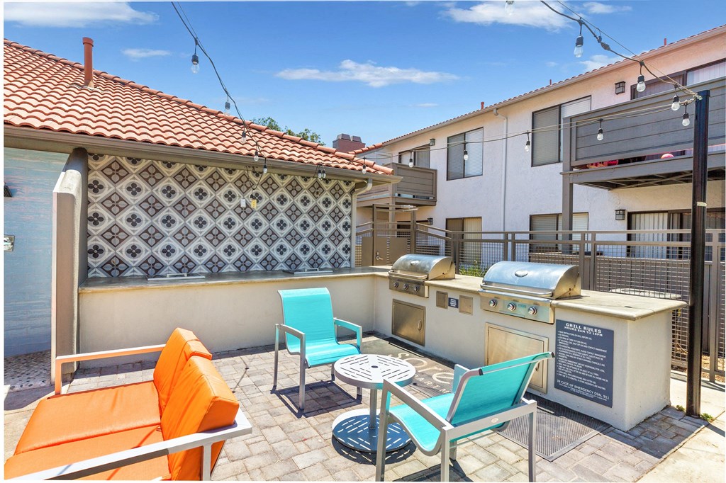 a patio with a barbecue grill and a table with chairs