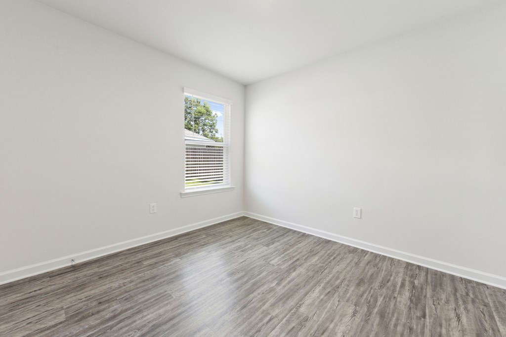 an empty room with white walls and wood floors and a window
