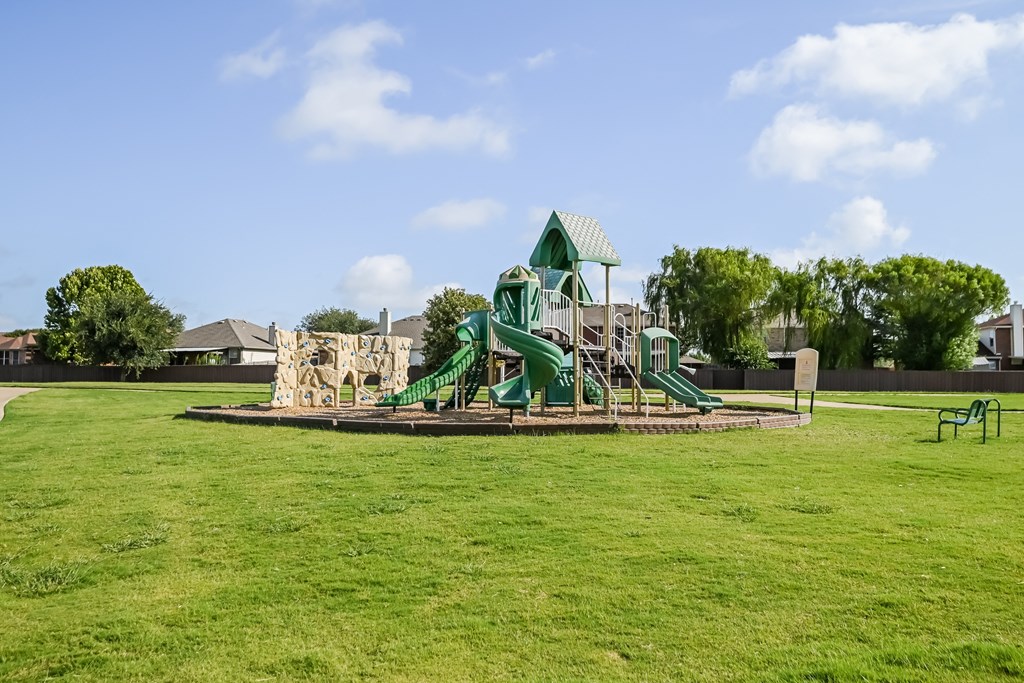 a large playground with a slide in the middle of a grass field