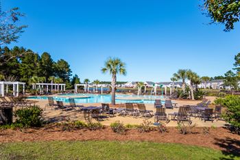 a resort style swimming pool with chairs and trees