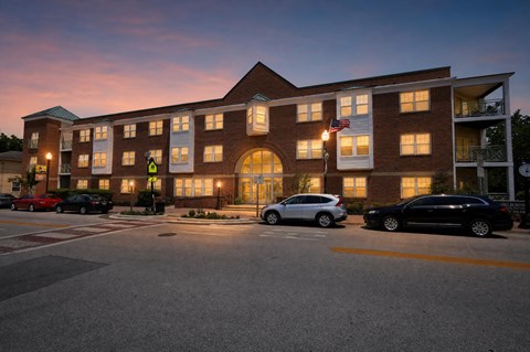 A building with a flag on it and cars parked in front.