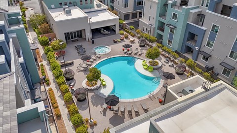 A swimming pool surrounded by a patio with chairs and umbrellas.