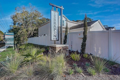 Terrapin Station single-family home rentals entrance sign with white fence and landscaping.