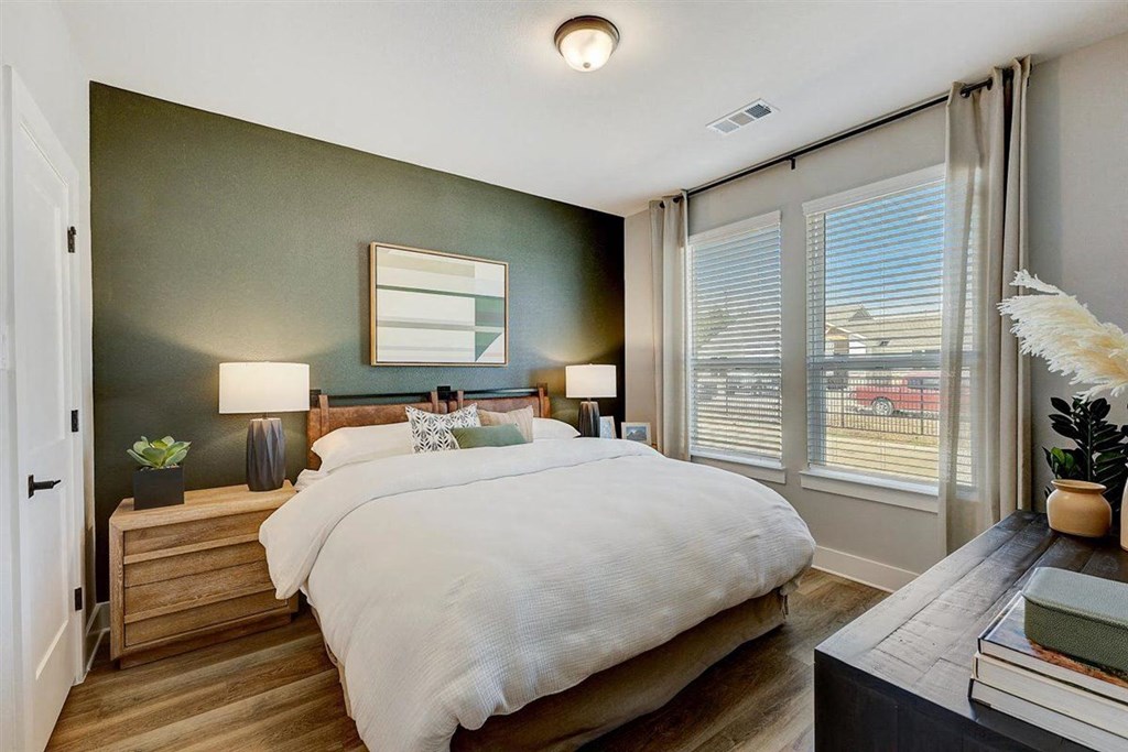 a bedroom with a large bed and two large windows