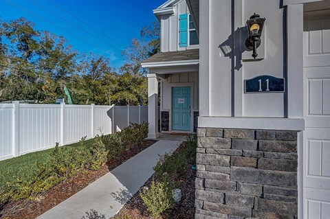 Exterior of a modern white house with a light blue door and "Open" sign.