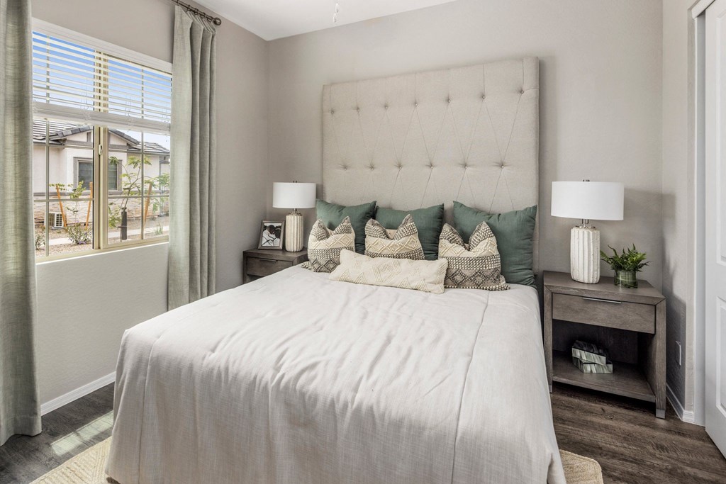 A bedroom with a large bed and a window with curtains.