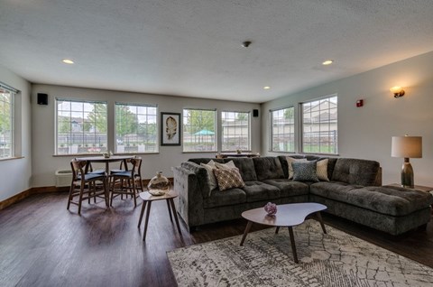 A living room with a grey couch, wooden chairs, and a coffee table.