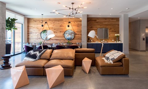 A living room with a brown leather couch and a wooden wall.