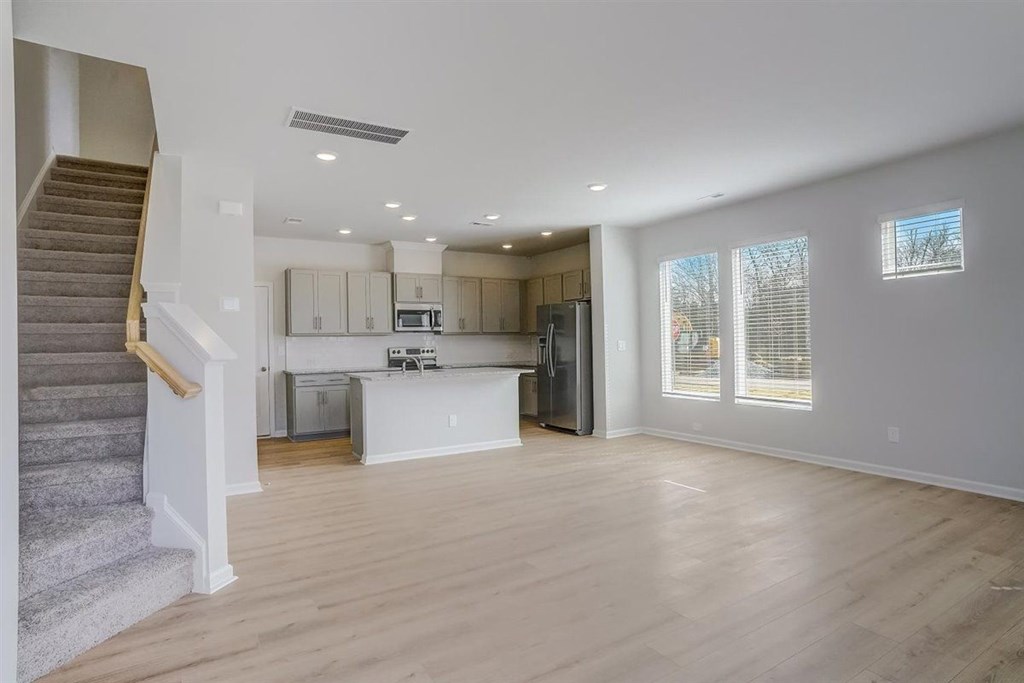 A spacious kitchen and living room with a staircase on the left side.