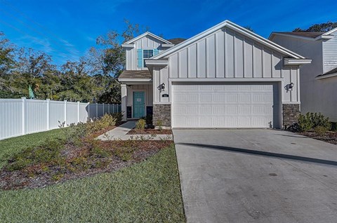 Modern two-story house with white vertical siding, turquoise door and shutters, and a white garage door.