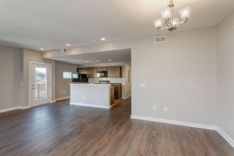 an empty living room with a kitchen and a door