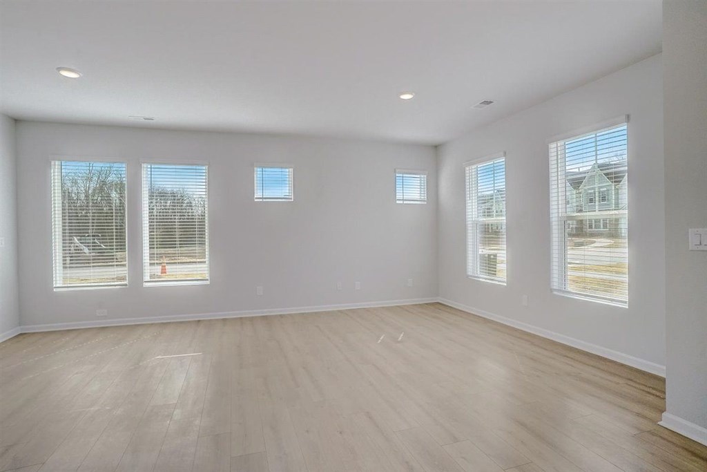 A large empty room with wooden floors and windows.