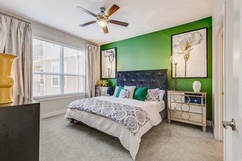 A bedroom with a bed, dresser, and ceiling fan.