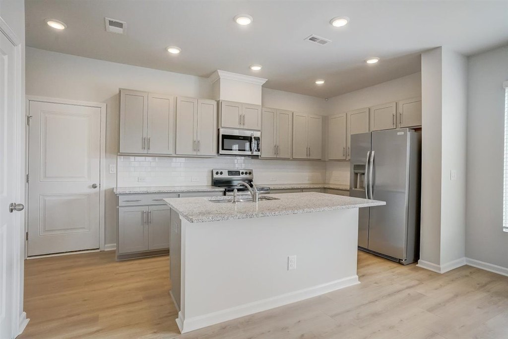 A kitchen with white cabinets and a marble island.