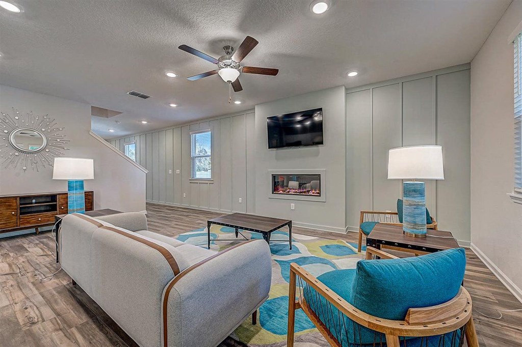 Modern living room with gray walls, fireplace, blue accents, and wood floors.