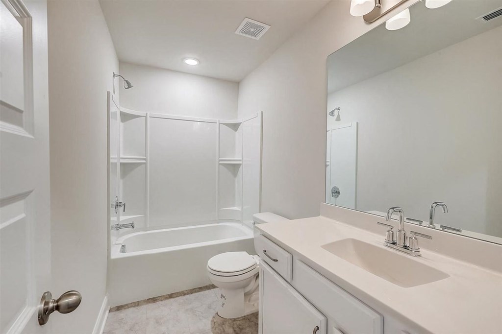 a bathroom with a white toilet next to a white bathtub