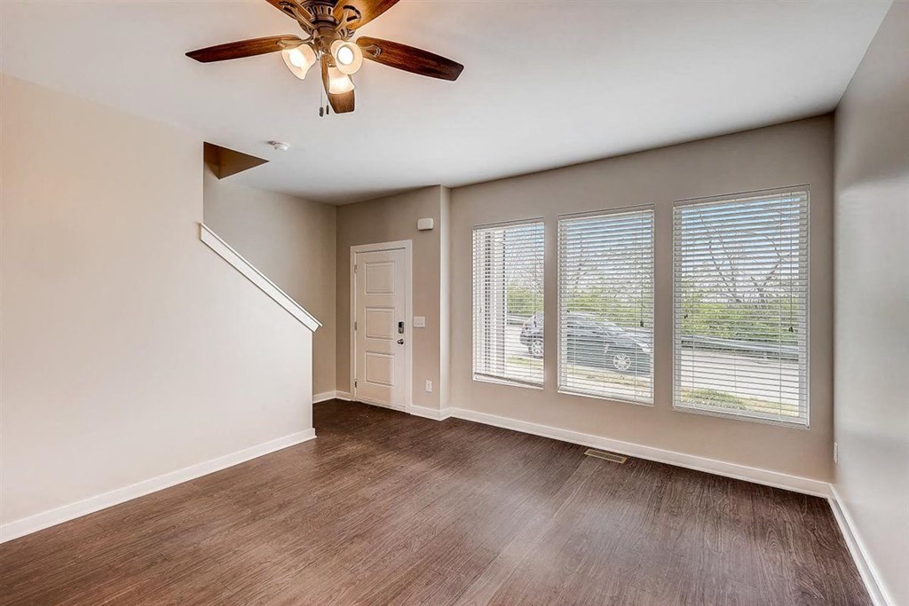 an empty bedroom with a ceiling fan and large windows