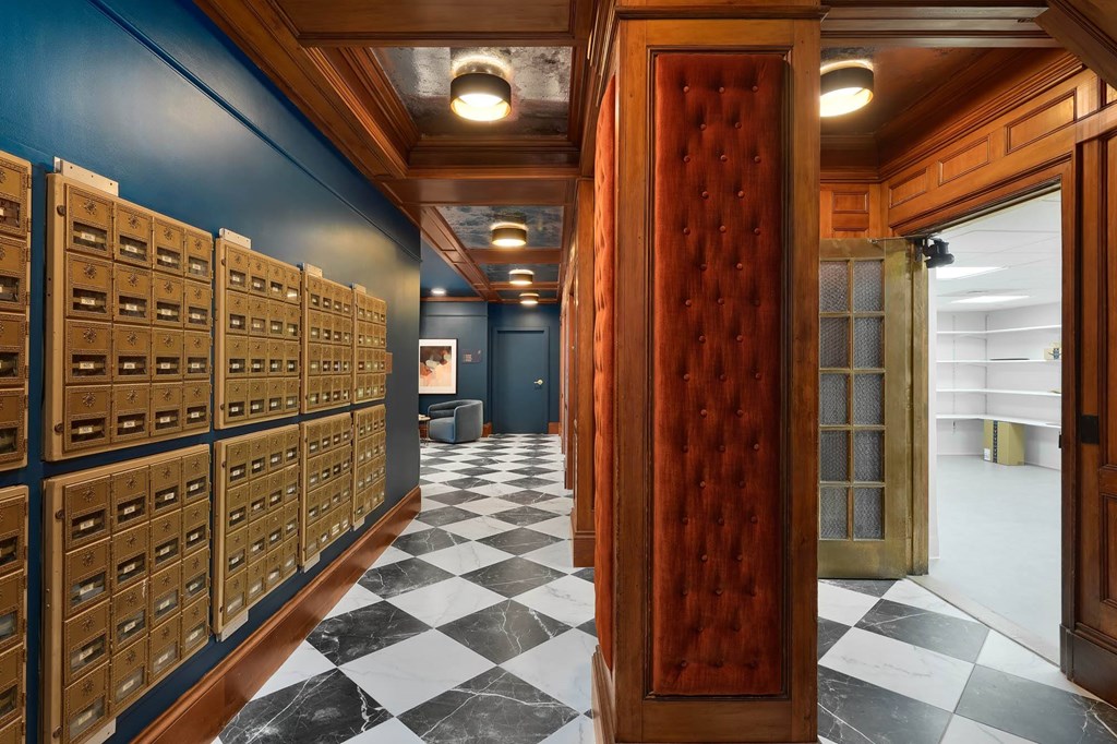 Hallway with brass mailboxes, checkered marble floor, and wood-paneled walls.