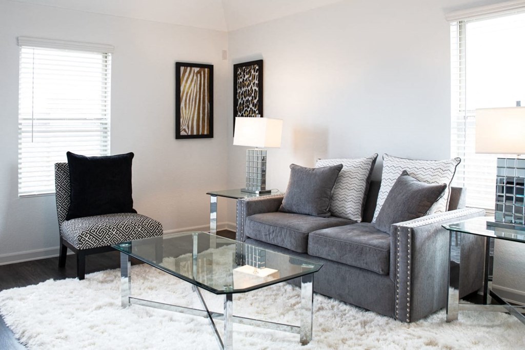 Houses in Humble for Rent - Edgewater at the Lagoon - Furnished Living Room with Wood-Style Flooring, Area Rug, Couch, Chair, Glass-Top Coffee Table and Side Tables, Two Windows, and Stylish Decor