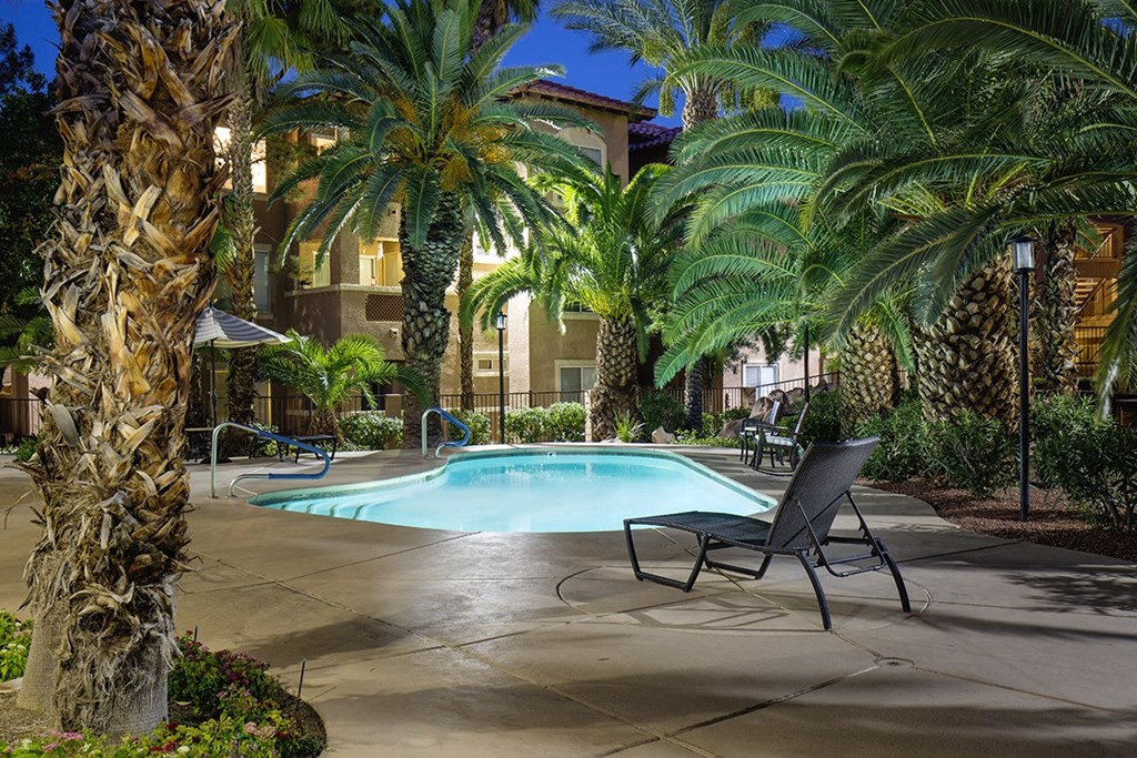 a swimming pool surrounded by palm trees and two chairs