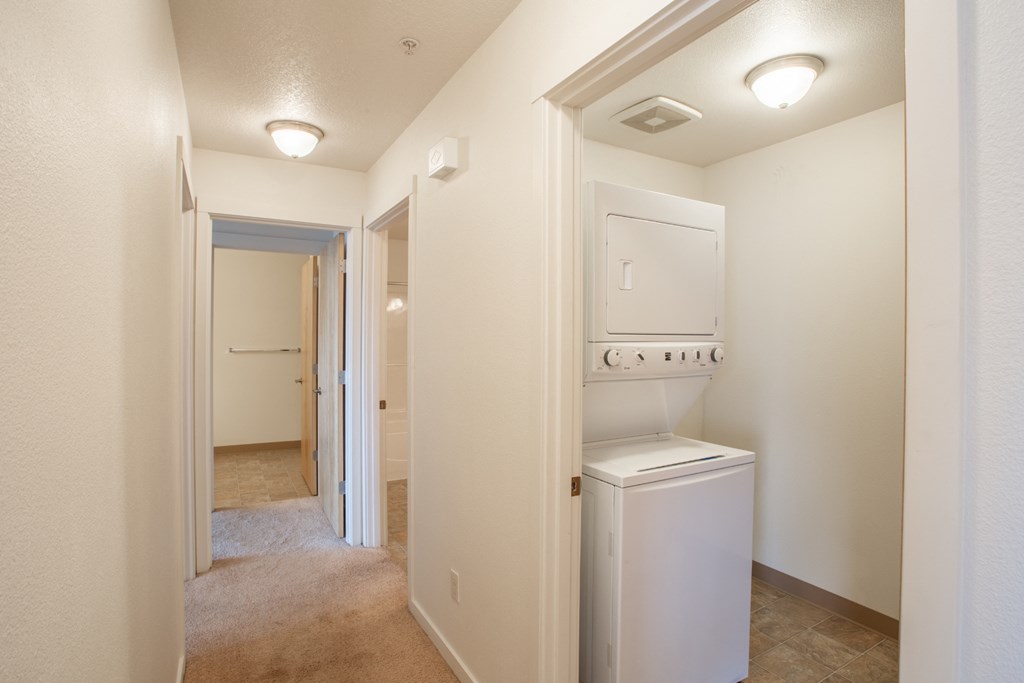 a laundry room with a washer and dryer and a hall to a bathroom